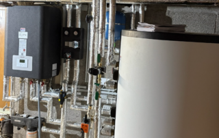 Blick in einen Heizungskeller mit neuverlegten Rohren, einem Kessel für Warmwasseraufbereitung.